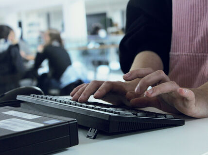 Henkilö kirjoittamassa tietokoneella