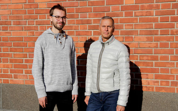 Joel Arantola ja Jouni Heikkinen seisovat punaista tiiliseinää vasten