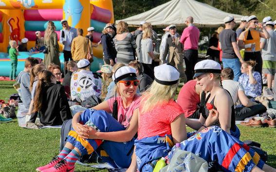 Opiskelijat istumassa nurmikolla haalareissa