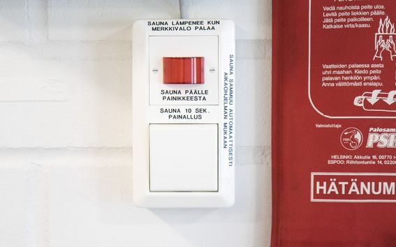 Valkoinen saunapainike seinään kiinnitettynä