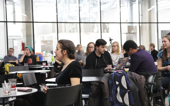 Ihmisiä istumassa pöytien ääressä tilaisuudessa. 