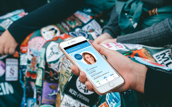 Person with overalls holding a phone with a digital student card on the screen