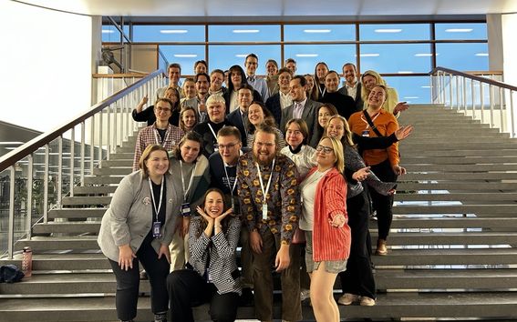 Many people standing and smiling for a group picture