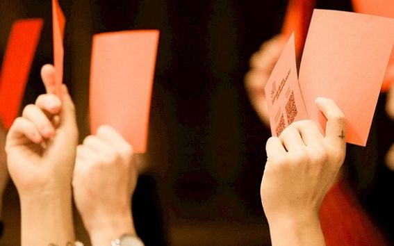 Kuva kokouksen äänestyslipukkeistä nostettuna.