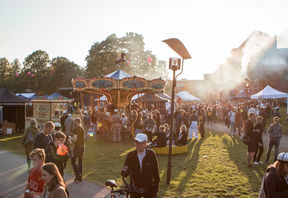 Ulkotapahtuma. Karuselli, auringonlasku, savua.