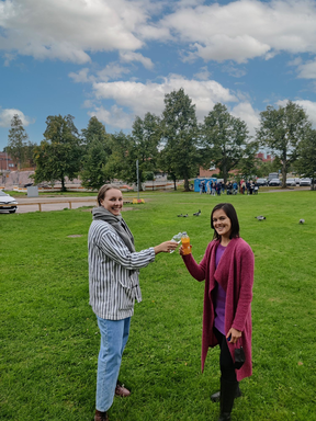 Rebecca and Fon are 'clinking glasses' with non-alcoholic beverages on Alvar Aallon Aukio-square. There are geese and students in the background.