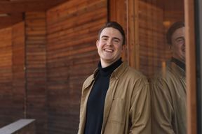 kuvassa Antti Regelin nojaa seinään ja hymyilee