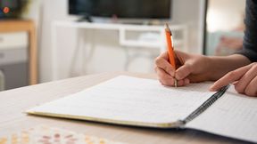Person's hands writing notes on a notebook with a pencil