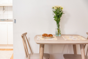 A kitchen table, flowers and cinnamon rolls on top.