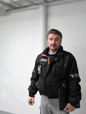 Maintenance Officer Janne Kankaisto looking at the camera with a laptop in his hand.
