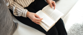 Woman's hands holding a book in her lap.