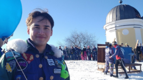 A male student in blue overalls looking in the camera