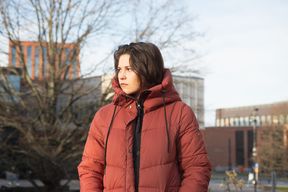 Kuvassa nuori naisoletettu seisoo Väreen edustalla kasvoillaan tuima ilme.