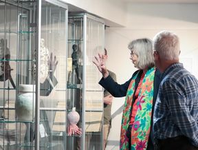 vanhempi naisoletettu osoittaa keraamisia taideteoksia Opiskelijakulttuurimuseon vitriineissä