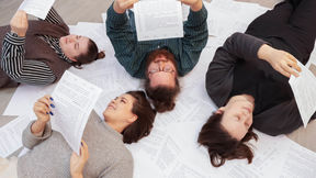 Four students laying on top of white paper and reading