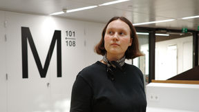 Mante at Väre building in front of a M letter, not smiling