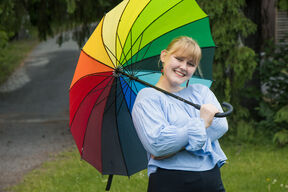 AYY Board's vice chair 2025 Elina Ståhlberg smiling and holding a rainbow colored umbrella