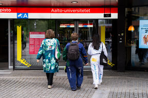 Kolme opiskelijaa kävelee kohti metroasemaa