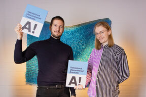 Two people with graduation folders