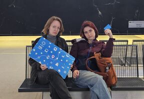 kaksi vihaisen näköistä naista metroasemalla, toisella on kädessään todella iso HSL-matkalippu
