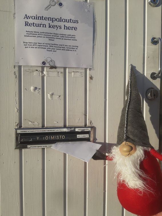 Joulutonttu laittaa avaimet postiluukusta kirjekuoressa