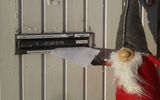 Joulutonttu laittaa avaimet postiluukusta kirjekuoressa
