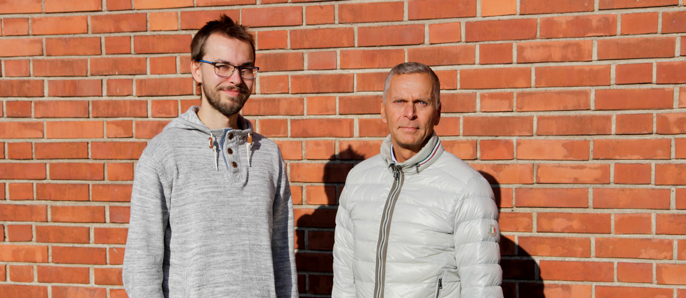 Joel Arantola ja Jouni Heikkinen seisovat punaista tiiliseinää vasten