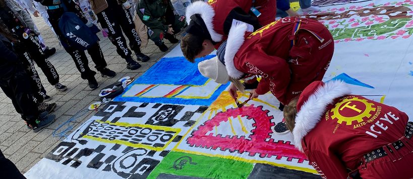 Kuvassa opiskelijat maalaavat lakanaan tekstiä "Iloista wappumieltä"