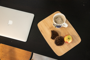 Laptop, teacup and snacks on a table.