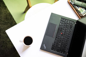 An open laptop on the table next to a coffee cup.