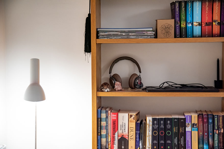 A lamp and a bookshelf with books and headphones.
